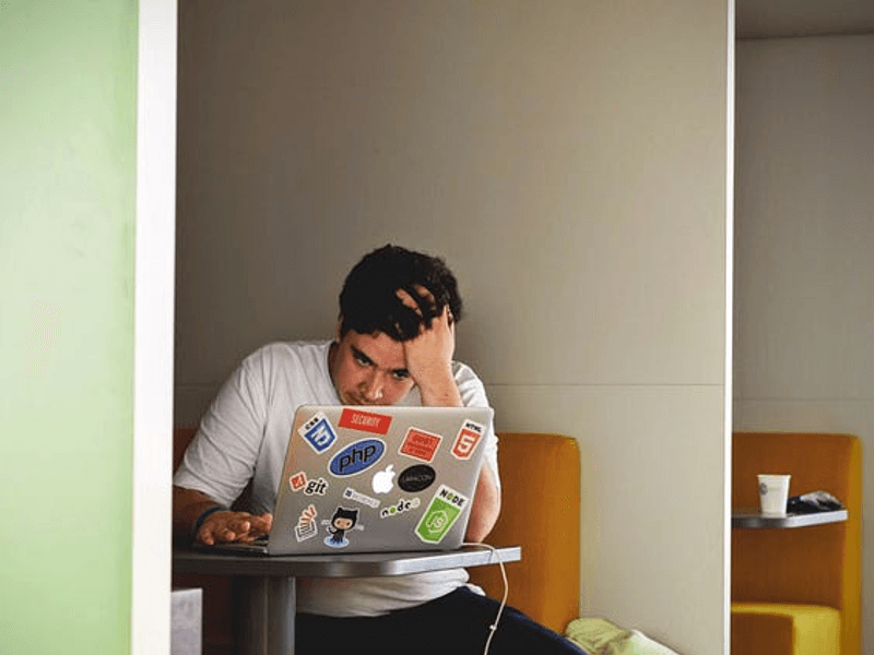 Man working in front of a laptop, looking very tensed.